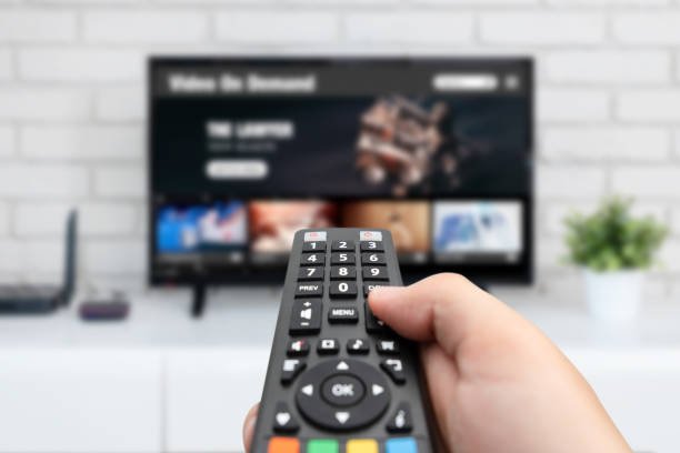 Man watching TV, remote control in hand. VOD service on TV